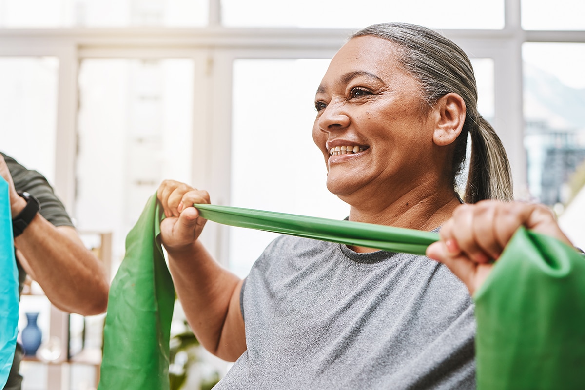 Physiotherapy, stretching band and senior couple with teamwork for muscle wellness, rehabilitation and support together. Elderly black people or friends smile in physical therapy with strong progress.